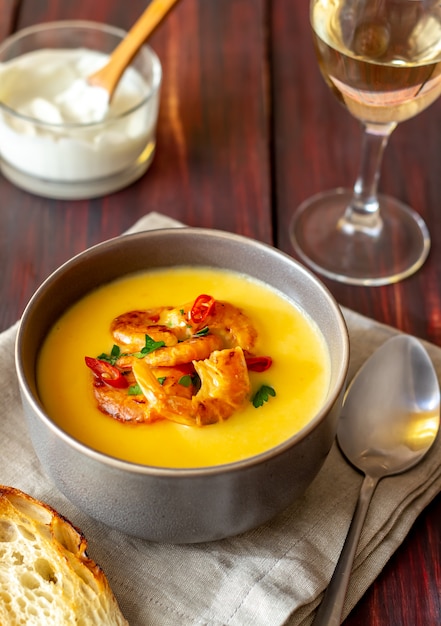 Zuppa di crema di formaggio con gamberi alla griglia su uno sfondo di legno.