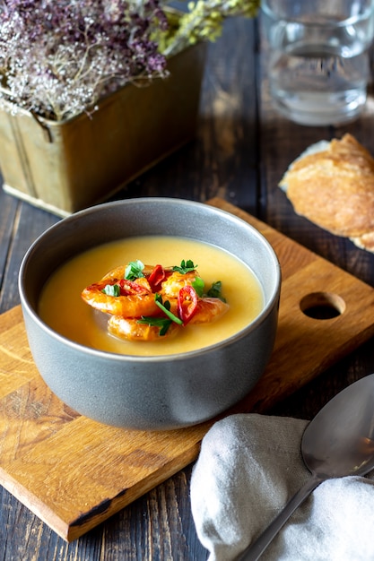 Zuppa di crema di formaggio con gamberi alla griglia su uno sfondo di legno.