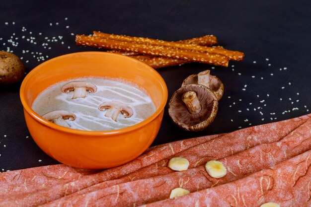 Zuppa di crema di funghi con una ciotola viola su un tavolo di legno scuro.