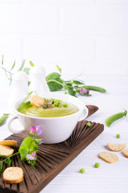 Zuppa di crema di piselli con crostini di pane in una ciotola bianca