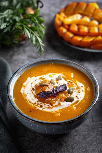 Zuppa di crema di zucca nella ciotola, primo piano. Fette di zucca alla griglia.