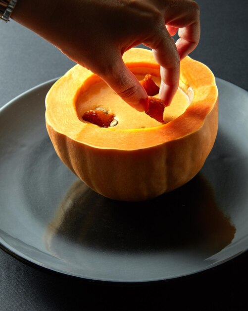 Zuppa di crema di zucca rossa biologica Uchiki kuri con prezzemolo su superficie nera