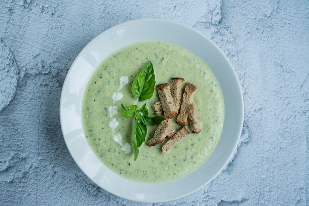 Zuppa di crema di zucchine servita in un piatto bianco.