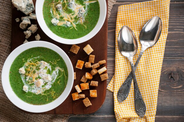 Zuppa di crema verde di spinaci e broccoli. con l'aggiunta di parmigiano e gorgonzola ai crostini. una superficie di legno.