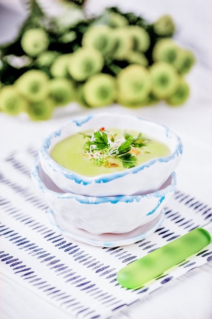 Zuppa di crema verde fatta in casa con foglie di prezzemolo di piselli e germogli di erba medica su un tavolo bianco