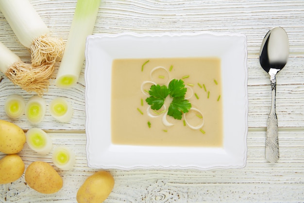 zuppa di crema vichyssoise con porri su legno bianco