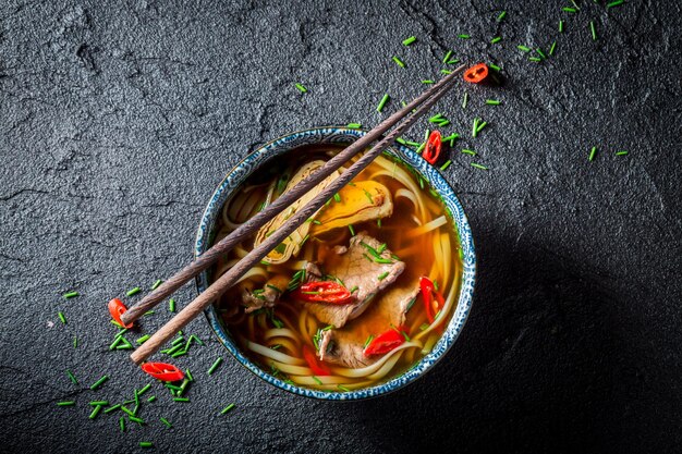 Zuppa di curry rosso con le bacchette sul tavolo nero