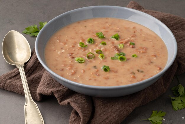 Zuppa di fagioli marroni in una ciotola con condimento su sfondo di pietra