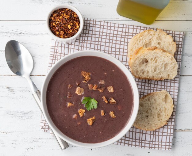 Zuppa di fagioli neri in una ciotola con fette di pane e condimento su un tavolo di legno