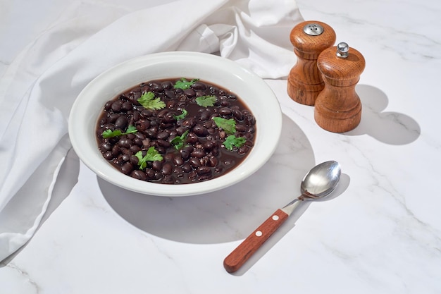 Zuppa di fagioli neri in una ciotola su un tavolo di marmo bianco