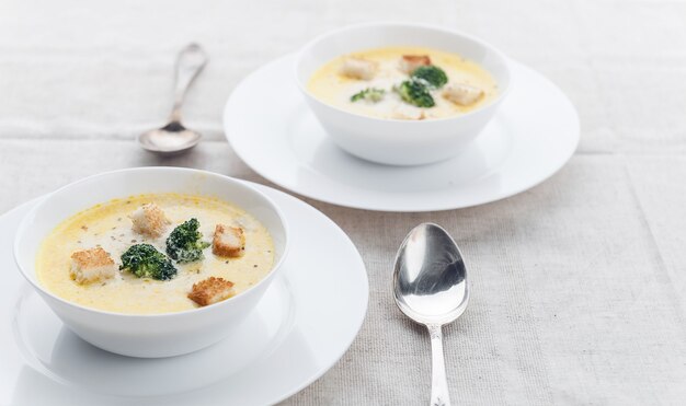 Zuppa di formaggio con broccoli in un piatto bianco su una tovaglia di lino bianca