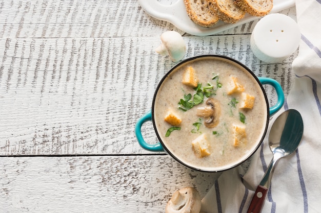 Zuppa di funghi champignon crema su tavola di legno bianco. Vista dall'alto. Spazio per il testo.