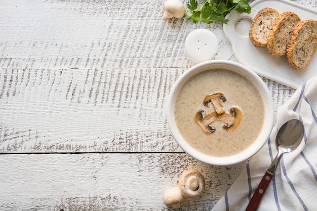 Zuppa di funghi champignon crema su tavola di legno bianco. Vista dall'alto Spazio per il testo.