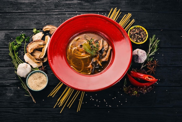 Zuppa di funghi con pasta di spaghetti Vista dall'alto su sfondo di legno nero Copia spazio