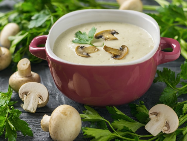 Zuppa di funghi con prezzemolo in una ciotola viola su un tavolo di legno scuro