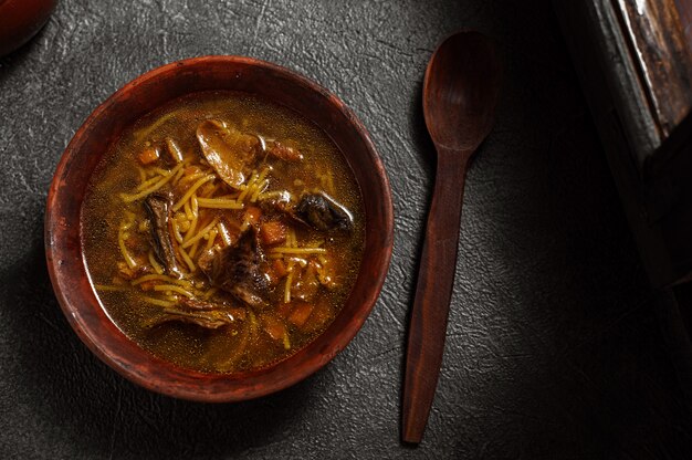 Zuppa di funghi fatta in casa su un tavolo vicino a una finestra in una vecchia casa rustica. Tradizioni nazionali, la ricetta della nonna per il cibo sano. Oscuro lunatico