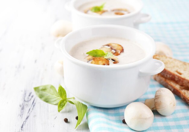 Zuppa di funghi in pentole bianche sul tovagliolo su fondo di legno