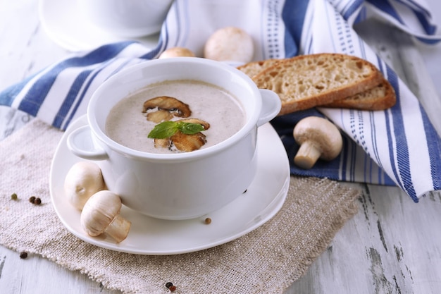 Zuppa di funghi in pentole bianche sul tovagliolo su fondo di legno