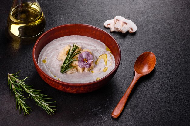 Zuppa di fungo bella deliziosa in un piatto marrone con un cucchiaio di legno su una superficie di marrone scuro