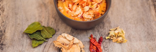 Zuppa di gamberi e citronella con cibo tailandese di igname di funghi nel banner di vista superiore del fondo di legno