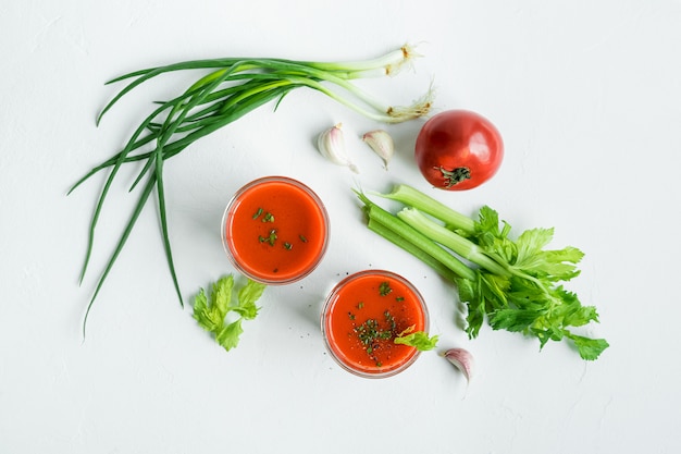 Zuppa di gaspacho spagnola tradizionale in bicchieri, ingredienti su bianco, vista dall'alto