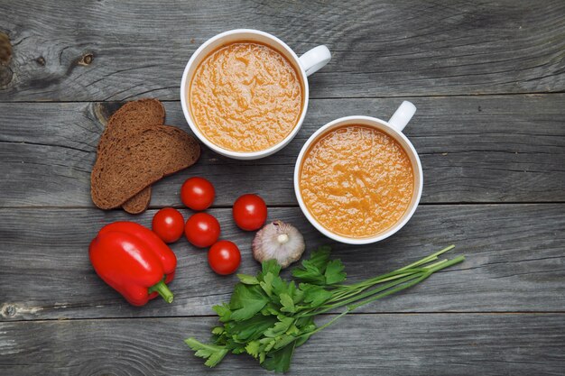 Zuppa di gazpacho e ingredienti sulla superficie in legno scuro