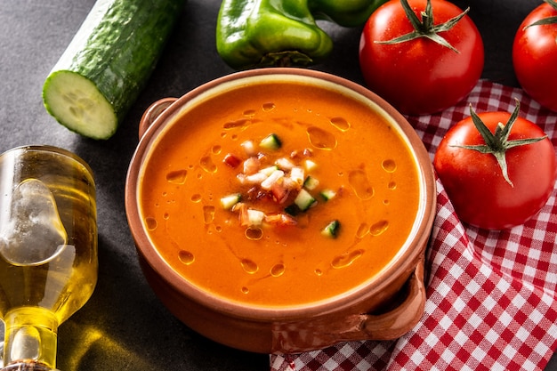 Zuppa di gazpacho in pentola e ingredienti sulla tavola di ardesia nera