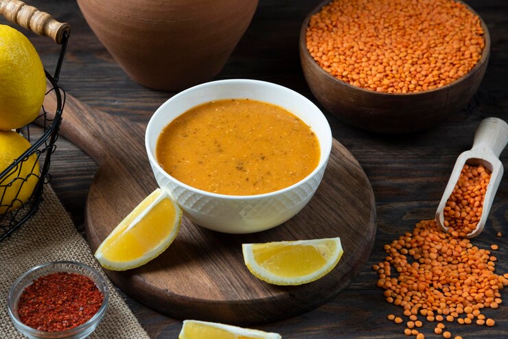 Zuppa di lenticchie con limone fresco e composizione in vaso di terracotta di lenticchie sul piatto di legno