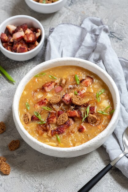 Zuppa di lenticchie e piselli guarnire con pancetta, cipolla fritta e crostini di pane