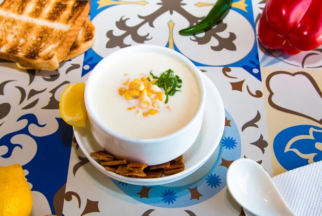 Zuppa di mais con biscotti al cucchiaio di lime e pane serviti in un piatto isolato sul tavolo vista del cibo arabo