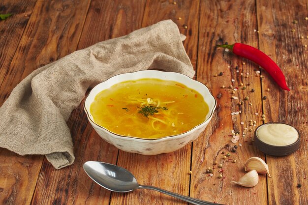 Zuppa di noodle in una ciotola, cucchiaio sul tavolo di legno