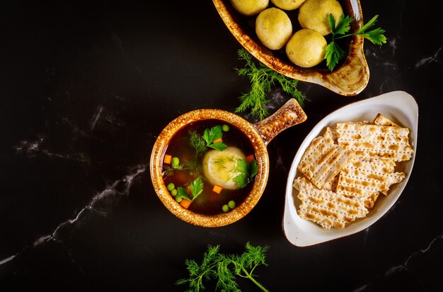 Zuppa di palline di matzo fatta in casa in due piatti con cucchiai sulla superficie nera.