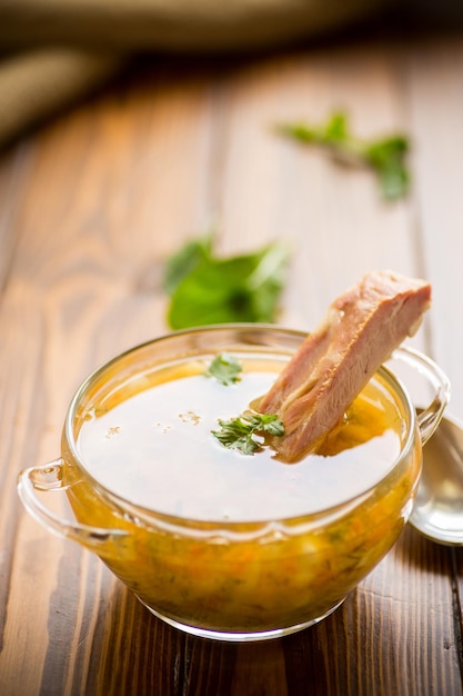 zuppa di piselli cotti con costolette affumicate in un piatto su un tavolo di legno