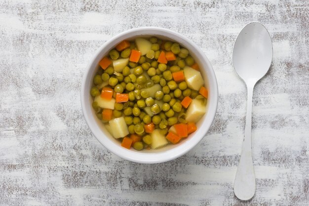 Zuppa di piselli e verdure in una ciotola bianca su fondo bianco