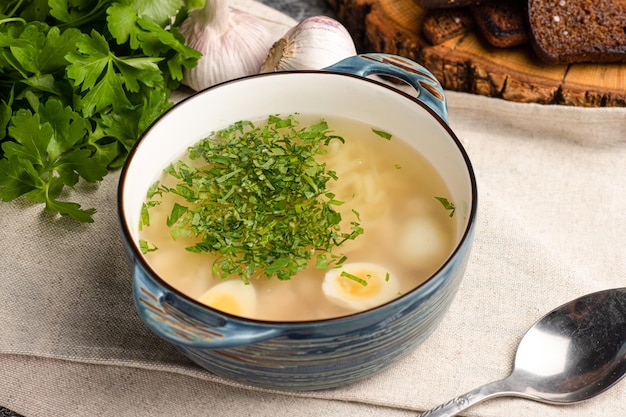 Zuppa di pollo con pollo ed erbe aromatiche su uno sfondo bianco di legno