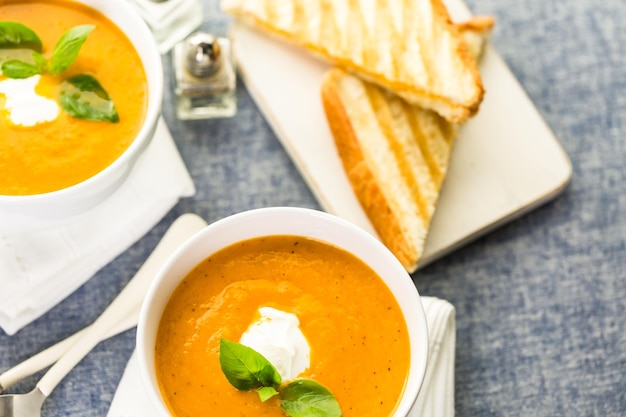 Zuppa di pomodoro arrosto cucinata con pomodori cimelio biologici e servita con sandwich al formaggio grigliato.