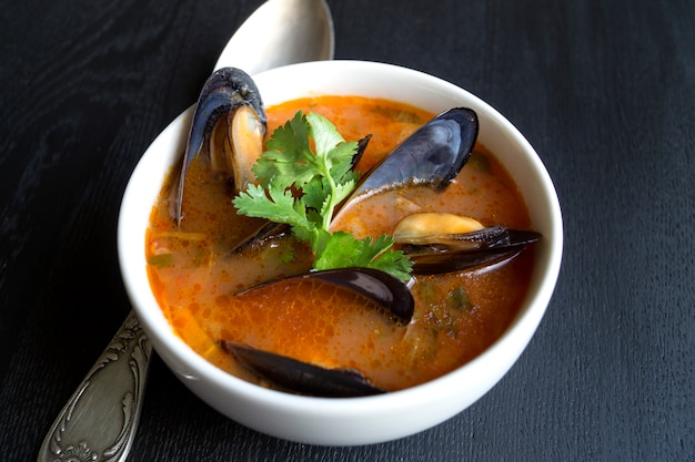 Zuppa di pomodoro con cozze, su uno sfondo nero.