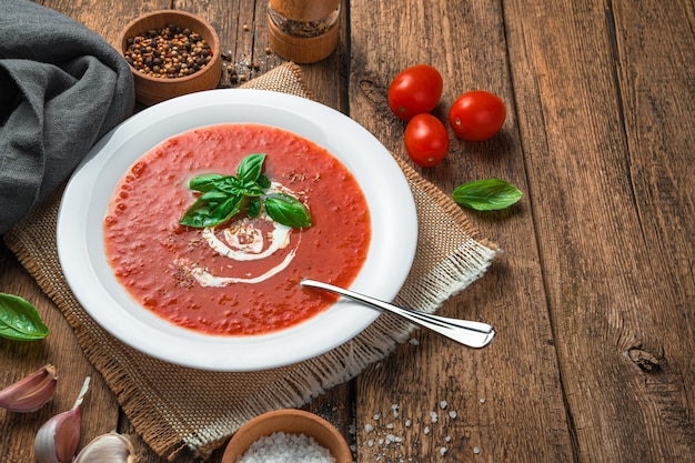 Zuppa di pomodoro fatta in casa con basilico e crema su uno sfondo di legno sano cibo biologico