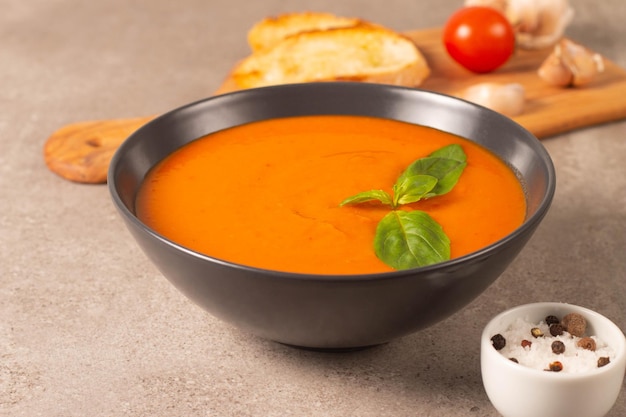 Zuppa di pomodoro fresca e sana con basilico pepe pomodori all'aglio e pane su fondo di legno