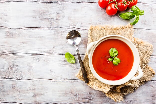 Zuppa di pomodoro in una ciotola bianca sulla tavola di legno, vista dall'alto