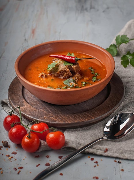 zuppa di pomodoro piccante con carne su sfondo grigio