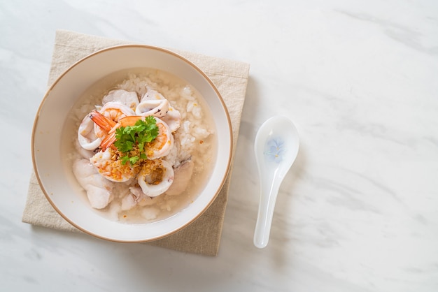 zuppa di porridge o riso bollito con ciotola di frutti di mare (gamberetti, calamari e pesce)