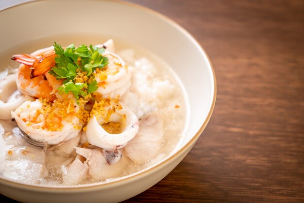 zuppa di porridge o riso bollito con ciotola di frutti di mare (gamberetti, calamari e pesce)