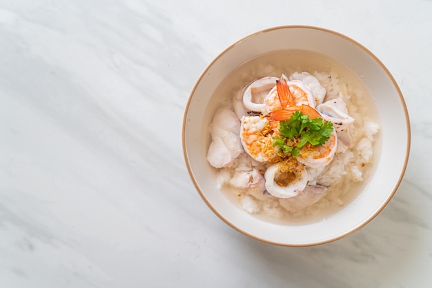 zuppa di porridge o riso bollito con scodella di pesce (gamberi, calamari e pesce)