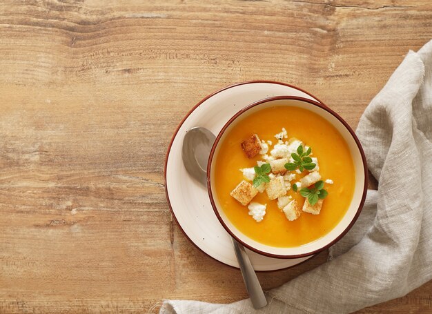 zuppa di purea di carote con formaggio e origano su un tavolo di legno vista dall'alto