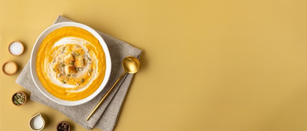 Zuppa di purea di zucca con banner ampio con toast alla crema e semi su sfondo colorato con spazio per la copia Concetto di cibo vegetariano vista dall'alto