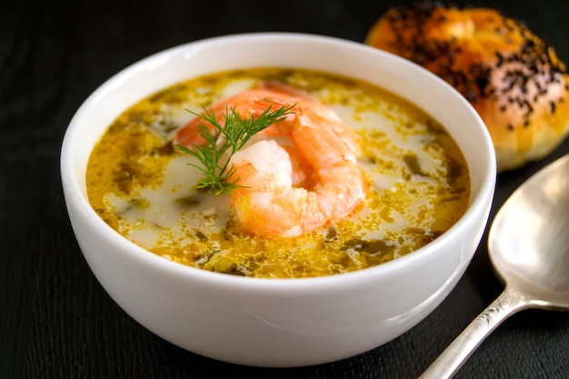 Zuppa di salmone con panna, patate, carote e aneto. su uno sfondo nero.