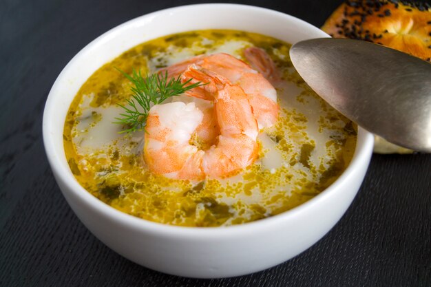 Zuppa di salmone con panna, patate, carote e aneto. su uno sfondo nero.