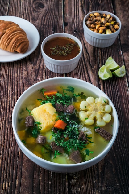 Zuppa di sancocho con carne di mais carote zucca yucca accompagnata da pane cancha serrana rocoto e