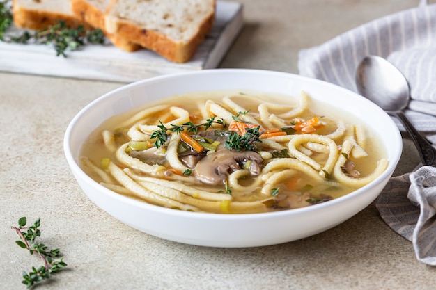 Zuppa di tagliatelle vegane con funghi e verdure servita con timo.